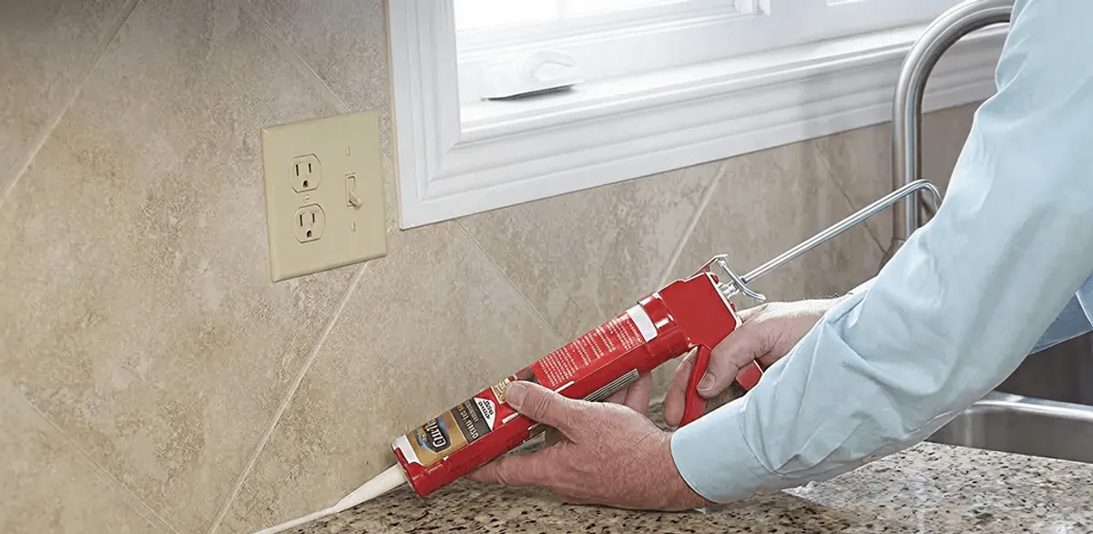 Handyman applying caulk along a kitchen backsplash and countertop seam in Cedar Rapids, IA